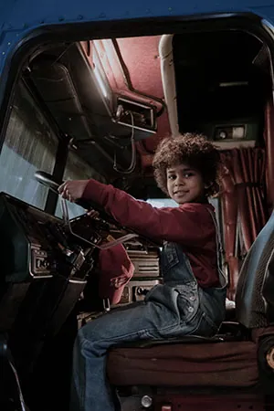 A child in a truck seat symbolizing, "Is the younger age for truck drivers putting more Pennsylvania drivers at higher risk?"